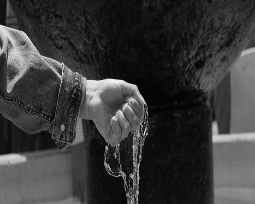 Detalle de unas manos sirviendo agua fresca, símbolo de hidratación